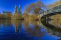 Bow Bridge in Central Park, New York in fall with Manhattan buildings in background and fallen leaves in the foreground Royalty Free Stock Photo