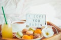 Romantic Breakfast in bed with I love you baby text on lighted box. Cup of coffee, juice, macaroons, flower and gift box on wooden Royalty Free Stock Photo