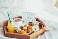 Romantic Breakfast in bed with I love you baby text on lighted box. Cup of coffee, juice, macaroons, flower and gift box on wooden Royalty Free Stock Photo