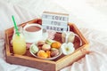 Romantic Breakfast in bed with I love you baby text on lighted box. Cup of coffee, juice, macaroons, flower and gift box on wooden