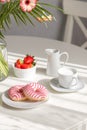 Romantic breakfast in the kitchen with a bouquet of flowers, donuts, coffee and fresh strawberries. Brunch on a sunny day Royalty Free Stock Photo