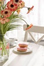 Romantic breakfast in the kitchen with a bouquet of flowers, donuts, coffee and fresh strawberries. Brunch on a sunny day Royalty Free Stock Photo