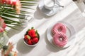 Romantic breakfast in the kitchen with a bouquet of flowers, donuts, coffee and fresh strawberries. Brunch on a sunny day. View Royalty Free Stock Photo