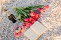 Romantic breakfast on the sandy beach. Photo session on a blanket with tulips and a book, donuts and champagne . Royalty Free Stock Photo