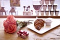 Romantic breakfast for Valentine`s Day celebrate. Present box, rose flowers, fresh croissant, wine on wooden table. Focus on crois Royalty Free Stock Photo