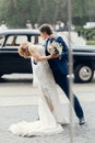 Romantic bride and groom portrait after wedding ceremony, happy newlywed couple dancing outdoors, luxury car in background, happy Royalty Free Stock Photo