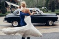 Romantic bride and groom portrait after wedding ceremony, happy newlywed couple dancing outdoors, luxury car in background, happy Royalty Free Stock Photo