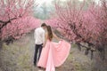 Romantic bridegroom kissing bride on forehead while standing against wall covered with pink flowers Royalty Free Stock Photo