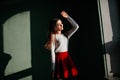 Romantic brown-haired lady enjoying sunlight while posing in the dark. Indoor photo of graceful white woman in trendy