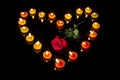 Romantic burning floral shaped candles in heart shape with a bright red rose at the center signifying love.