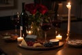 A romantic, candlelit setting, showcasing a bottle of red wine, accompanied by two wine glasses, a charcuterie board, and a Royalty Free Stock Photo