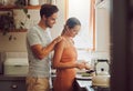 Romantic, caring and loving young couple supporting each other while preparing a meal in the kitchen. Man and woman in a Royalty Free Stock Photo