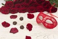 Romantic carnival concept. Red carnival mask, bouquet of red roses and chocolates on light wooden background