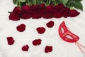 Romantic carnival concept. Red carnival mask, bouquet of red roses and scattered petals on white fur