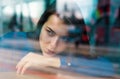 Romantic casual woman portrait. Thoughtful concept. Woman at a cafe while gazing through the window glass. Sad alone