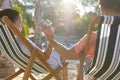 Romantic caucasian young couple holding hands and relaxing on deck chairs at beach Royalty Free Stock Photo