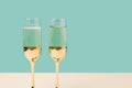 Romantic champagne glasses set up on a turquoise background.