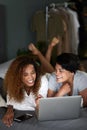 A romantic comedy is always a winner with us. a young couple using a laptop while lying on their bed.