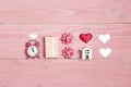 Romantic composition with alarm clock, gift, miniature house and hearts on pink wooden background