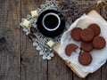 Romantic composition of chocolate cookies with white cream, cup of coffee and bouquet lavender on wooden background. Selective foc Royalty Free Stock Photo