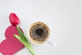 Romantic composition with cup of coffee and red tulip on white background. Royalty Free Stock Photo