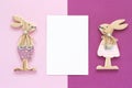 Romantic composition Pair of wooden lovers figurine rabbits and white blank card for text on pink purple background Concept