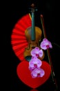 Romantic concept with violin, heart shape gift box, red folding fan and pink orchids Royalty Free Stock Photo