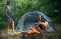 Romantic couple camping on nature background. Adventure for young friends on summer day. Carefree coupl near campfire