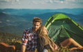 Romantic couple camping outdoors and sitting near tent. Happy Man and woman on a romantic camping vacation. Young couple Royalty Free Stock Photo