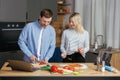 Romantic couple is cooking on kitchen. Handsome man and attractive young woman are having fun together while making salad and Royalty Free Stock Photo