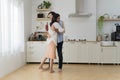 Romantic couple dancing in kitchen. Playful full length beautiful young couple in casual clothes dancing and smiling while Royalty Free Stock Photo