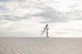 Romantic couple dancing in sand desert. The guy lifts the girl above himself. Sunset sky Royalty Free Stock Photo