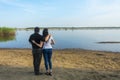 A romantic couple in an embrace stand in the summer on the river bank and watch the sunset. Romance concept Royalty Free Stock Photo