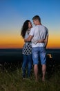 Romantic couple embrace at sunset, beautiful landscape and bright yellow sky, love tenderness concept, young adult people backside Royalty Free Stock Photo