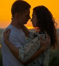 Romantic couple embrace at sunset on outdoor, beautiful landscape and bright yellow sky, love tenderness concept, young adult Royalty Free Stock Photo