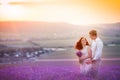 Romantic couple in an endless lavender field at sunset. blond Man and red-haired girl with a bouquet of flowers in love Royalty Free Stock Photo