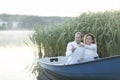 Romantic couple enjoys time sitting in boat, sailing in water,pointing fingers away. Happy Royalty Free Stock Photo