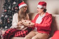 Romantic couple exchanging gifts near decorated christmas tree. Man giving christmas present surprise to smiling woman Royalty Free Stock Photo