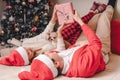 Romantic couple exchanging gifts near decorated christmas tree. Man giving christmas present surprise to smiling woman in sweater Royalty Free Stock Photo