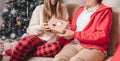 Romantic couple exchanging gifts near decorated christmas tree. Man giving christmas present surprise to smiling woman in sweater Royalty Free Stock Photo