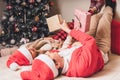 Romantic couple exchanging gifts near decorated christmas tree. Man giving christmas present surprise to smiling woman in sweater Royalty Free Stock Photo