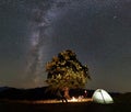 Couple tourists at night camp in mountains under starry sky Royalty Free Stock Photo