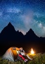 Romantic couple hikers looking to the shines starry sky and Milky way in the camping at night near campfire Royalty Free Stock Photo