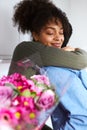Romantic couple at home with man surprising woman with bunch of flowers celebrating valentines day, birthday or anniversary and
