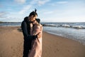 Romantic couple hugging on the beach on sunset. Soft sunny colors. Cold autumn weather. Royalty Free Stock Photo