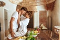 Romantic Couple At Kitchen. Beautiful Woman Sitting On Wooden Table And Hugging Standing Man.