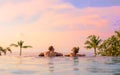 Romantic couple looking at beautiful sunset in luxury infinity pool Royalty Free Stock Photo