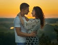 Romantic couple looking at each other at sunset on outdoor, beautiful landscape and bright yellow sky, love tenderness concept, yo