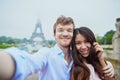 Romantic couple in love taking selfie near the Eiffel tower in Paris on a cloudy and foggy rainy day Royalty Free Stock Photo