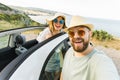 Romantic couple making selfie on smartphone camera in rental cabrio car on ocean or sea beach enjoying summer vacation Royalty Free Stock Photo